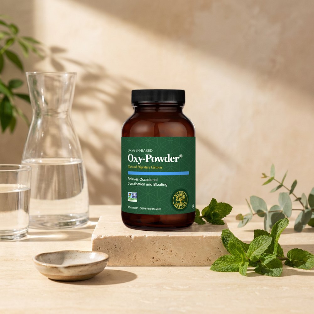 Oxy-Powder bottle on a stone pedestal in morning sunlight with a water carafe and fresh mint