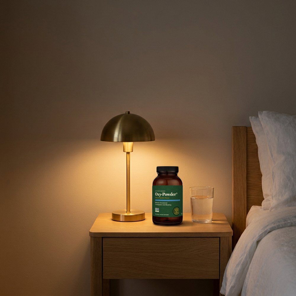 The Oxy-Powder bottle on a nightstand beside a lamp and a glass of water